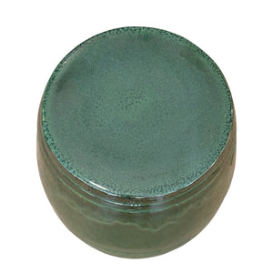 The Olive Green Cylinder Stool features a round, porcelain design with a smooth, glazed surface and matching top, seen from above.