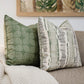 Two Da Da Stripe Cactus Pillows, custom-made from the finest materials, sit on a beige couch next to a textured knit blanket, with a framed nature-themed artwork in the background. The attention to detail is evident in every element of this cozy setup.