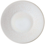 A round, off-white ceramic plate with a slightly textured pattern radiating from the center to the edges, exuding timeless elegance from the Jars Vuelta White Pearl Collection.