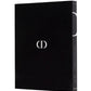 A black book with a white "CD" logo on the cover and "Dior: Yves Saint Laurent" written on the spine, showcasing haute couture.