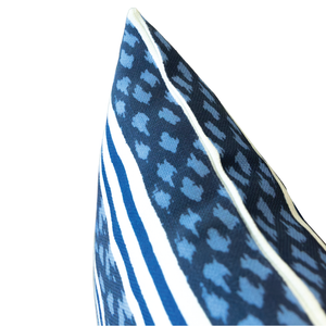 Close-up of the corner of the Banita Outdoor Lumbar Pillow, featuring weather-resistant material with blue and white striped and dotted abstract patterns, accented by white piping, isolated on a white background.