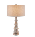 The Petra Table Lamp in Rainbow Sandstone features a cylindrical beige fabric shade and a sculpted light wood base with an elegant design, shown against a white background.