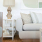 A modern living room featuring a light gray sofa adorned with **Foliage Mushroom Pillows**, a geometric white side table with decorative items, and a metallic table lamp against a minimalist wall art backdrop. The attention to detail in choosing the finest materials creates an inviting and elegant space.