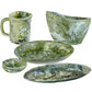 The Nashi Home Serveware Collection, Forest, features five green and white marbled resin pieces—a mug, large bowl, shallow bowl, and two plates—perfect as an elegant serving set for contemporary home decor.