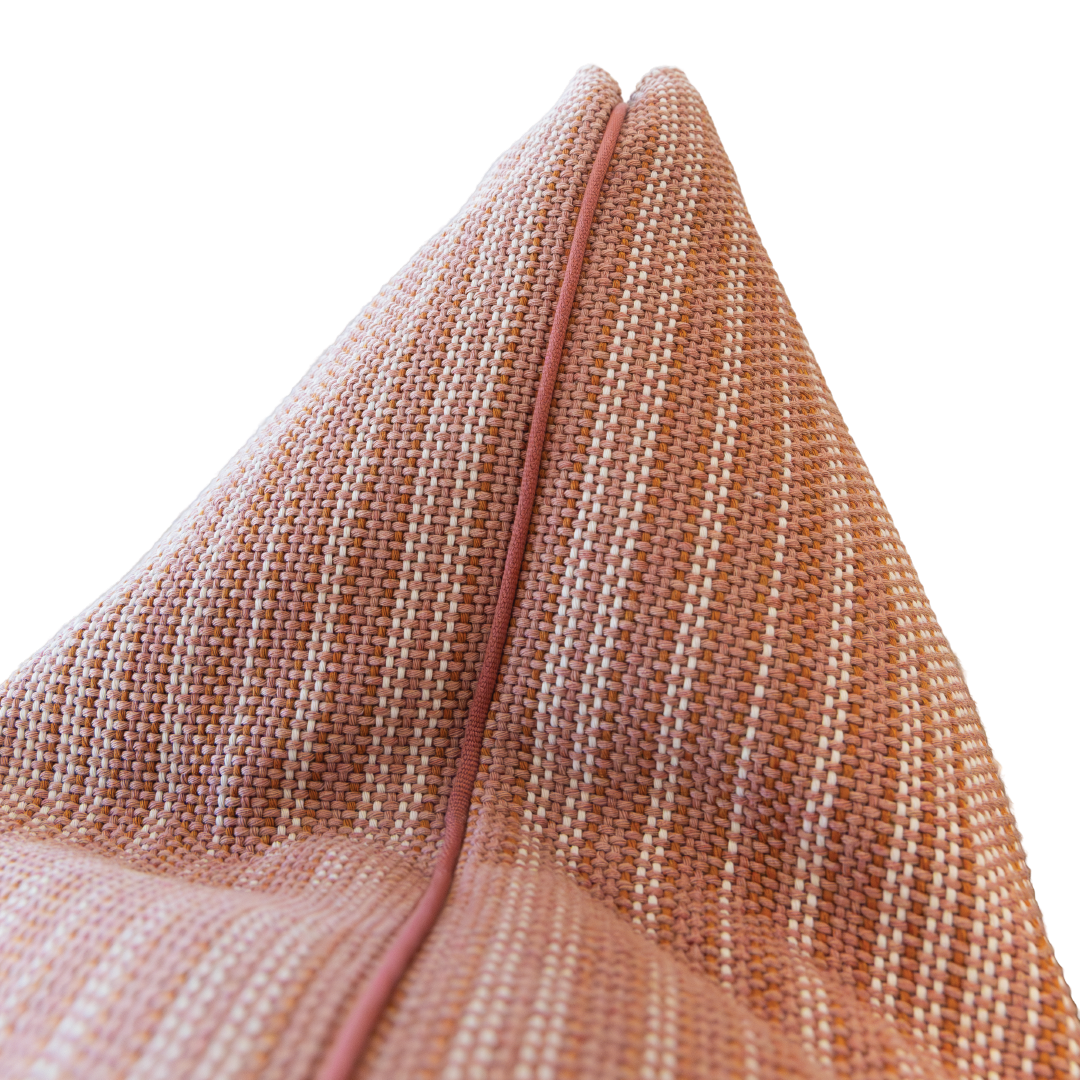 Close-up of the Avia Terracotta Pillow, a 22x22 inch pillow crafted from textured, woven fabric in peach tones with a central seam, set against a white background.