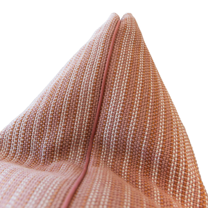 Close-up of the Avia Terracotta Pillow, a 22x22 inch pillow crafted from textured, woven fabric in peach tones with a central seam, set against a white background.