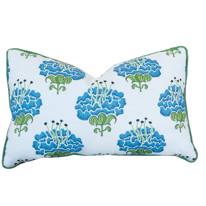 The Peony Bluebell Lumbar Pillow is a rectangular white pillow adorned with blue and green floral patterns and finished with green piping along the edges. It features a hidden zipper closure for a seamless appearance and is shown against a plain background.