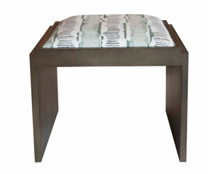 A Munstead Ottoman with a rectangular cushion featuring a green, white, and black pattern showcases custom upholstery for a unique touch.