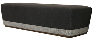 A rectangular, dark gray Harlow Bench with maze tape trim at the base, resting on a wooden frame.