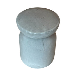 The Gray/White Pedestal Stool features a round, gray concrete design with a smooth finish and simple cylindrical shape, echoing the look of classic porcelain garden stools.