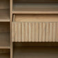 Close-up of the Anton Bar drawer featuring a grooved vertical design, highlighted natural wood grain, and surrounded by shelves for smart storage solutions.
