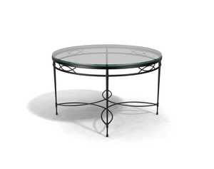 The Amalfi Glass Top Round Dining Table features a hand-forged steel frame with decorative curved details, creating a striking shadow on a white background.