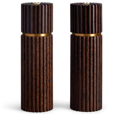 Two dark brown wooden cylindrical L'Objet Ionic Salt and Pepper Mills, crafted from European oak with vertically grooved patterns, feature gold bands near the top and a metal grinding mechanism.