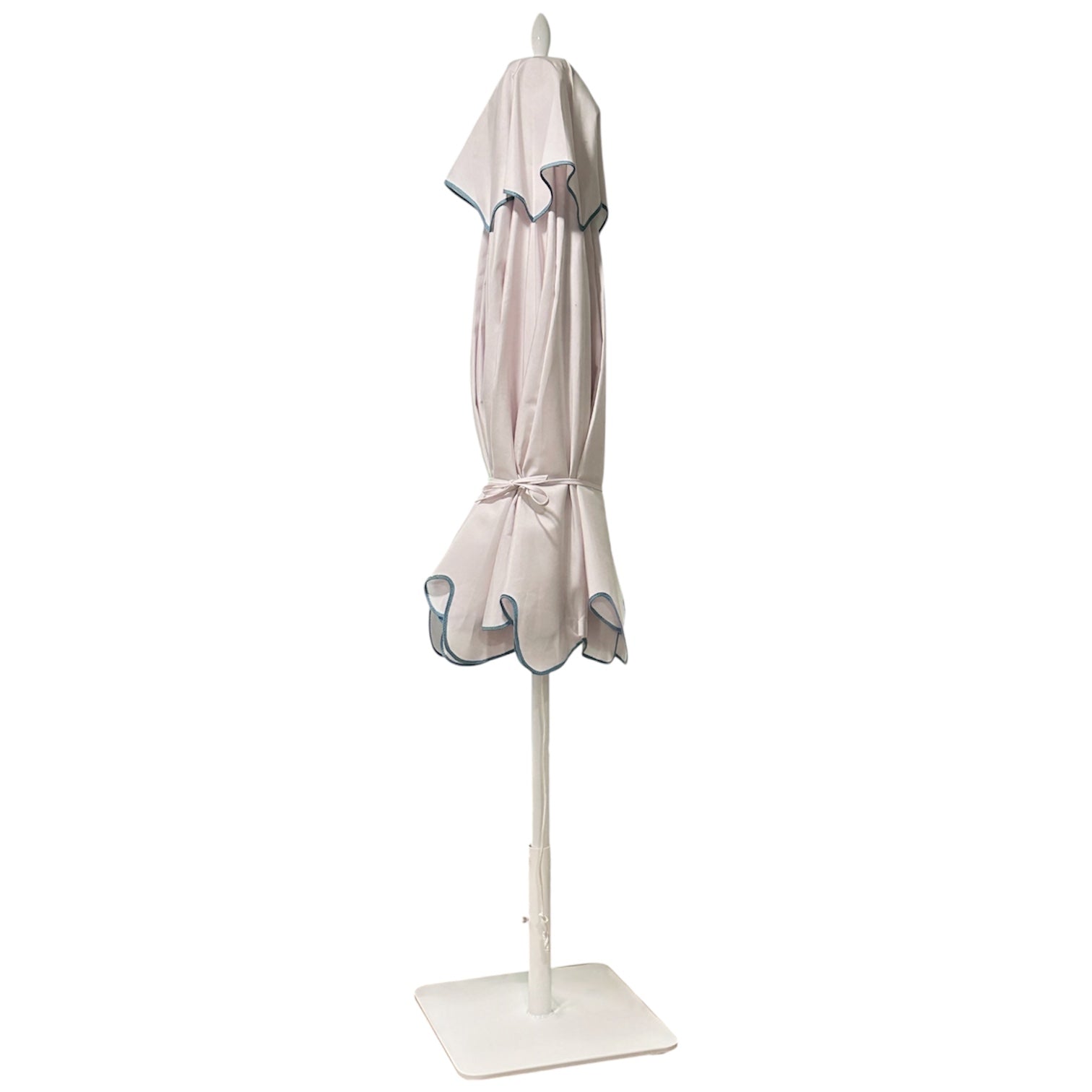 The Montecito Hex Umbrella stands upright on a white base, featuring light-colored fabric and dark trim—an elegant showcase of Santa Barbara’s refined style.