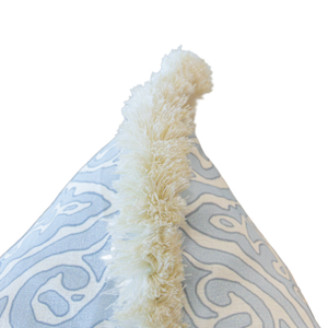 Close-up of the Diamond Batik Blue Pillow, showcasing its light blue and white patterned design with a vertical row of ivory fringe trim along the top seam, featuring a hidden zipper closure and isolated on a white background.