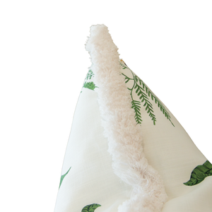 A close-up of the Woodland Fern Outdoor Pillow, featuring green fern leaf patterns on a white background with a fluffy white trim and a hidden zipper closure.