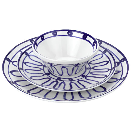 Three dishes from the Themis Z Kyma Blue Collection—bowl, salad plate, and dinner plate—are stacked, featuring white ceramic with blue abstract lines inspired by the Greek Aegean Sea.