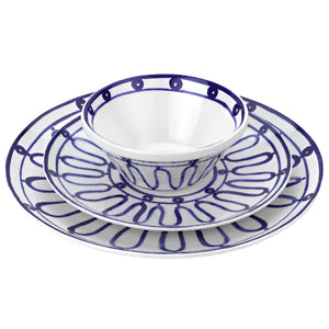 Three dishes from the Themis Z Kyma Blue Collection—bowl, salad plate, and dinner plate—are stacked, featuring white ceramic with blue abstract lines inspired by the Greek Aegean Sea.
