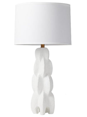 The Julius Table Lamp, White Resin features a modern white design with a sculptural base crafted from textured resin and is topped with a cylindrical fabric lampshade.