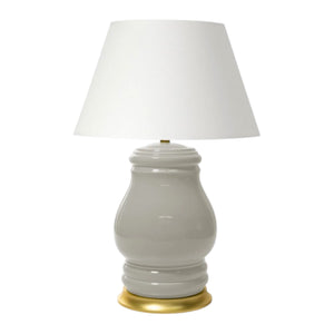 The Charleston Table Lamp in Greige showcases a glossy, curvy ceramic base with a gold-toned rim and a wide white fabric shade, creating an elegant look that adds a cozy ambiance to any room.