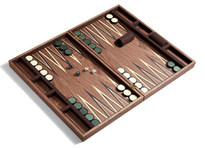 A hand-crafted Matis Backgammon Set with light and dark checkers, two dice, and a dice cup. The board is open and laid flat, displaying the triangular patterns in natural wood.