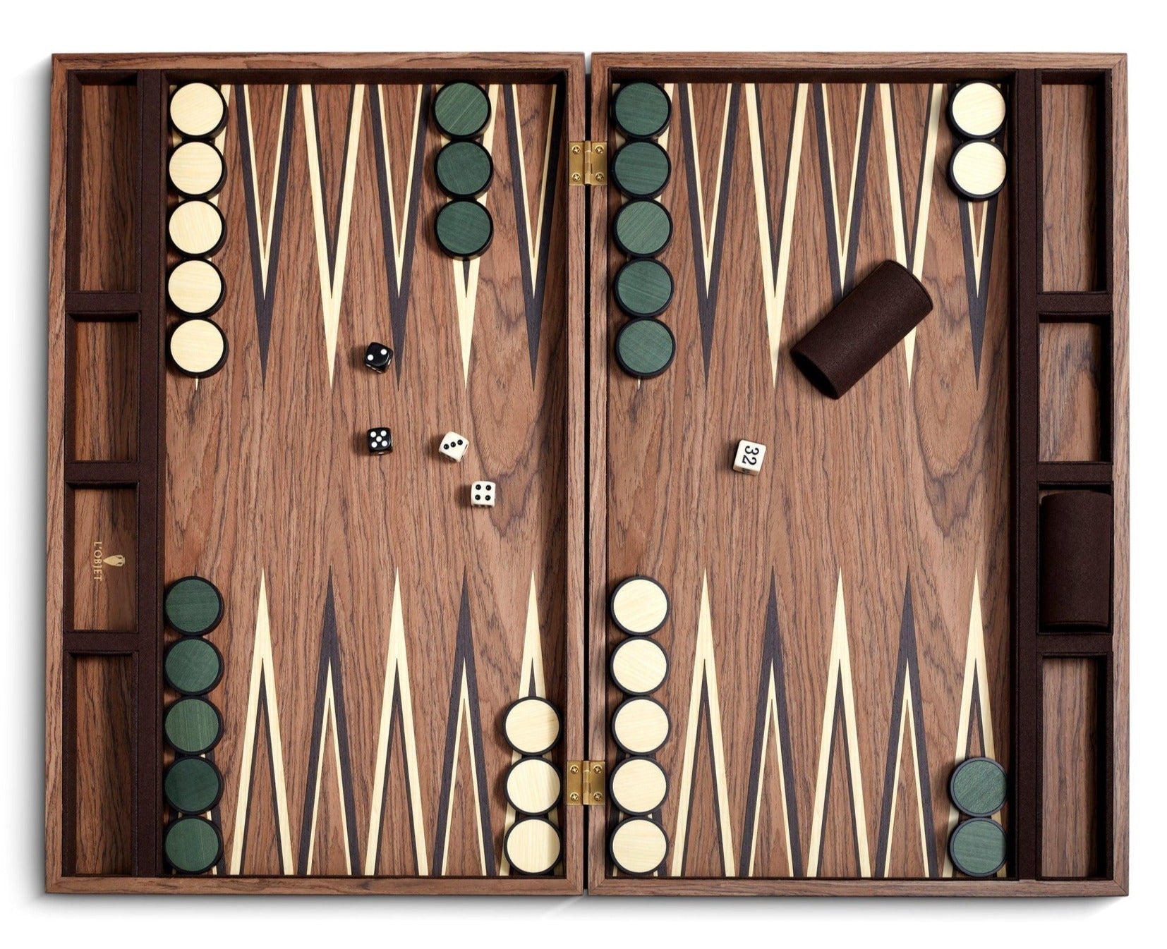 A Matis Backgammon Set featuring hand-crafted green and white checkers, two dice, and a tan doubling cube. There's also a dice cup on the right. The board boasts a natural wood design with triangular points.