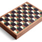 A rectangular wooden box with a checkered pattern on the lid, featuring alternating dark brown, beige, and green squares. Hand-crafted from natural wood, it evokes the elegance of a classic Matis Backgammon Set.