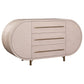 The Mullinex Low Cabinet in White Rustic Pine features an oval shape, three central drawers with long brass handles, and stands on four brass legs for ample storage and style.