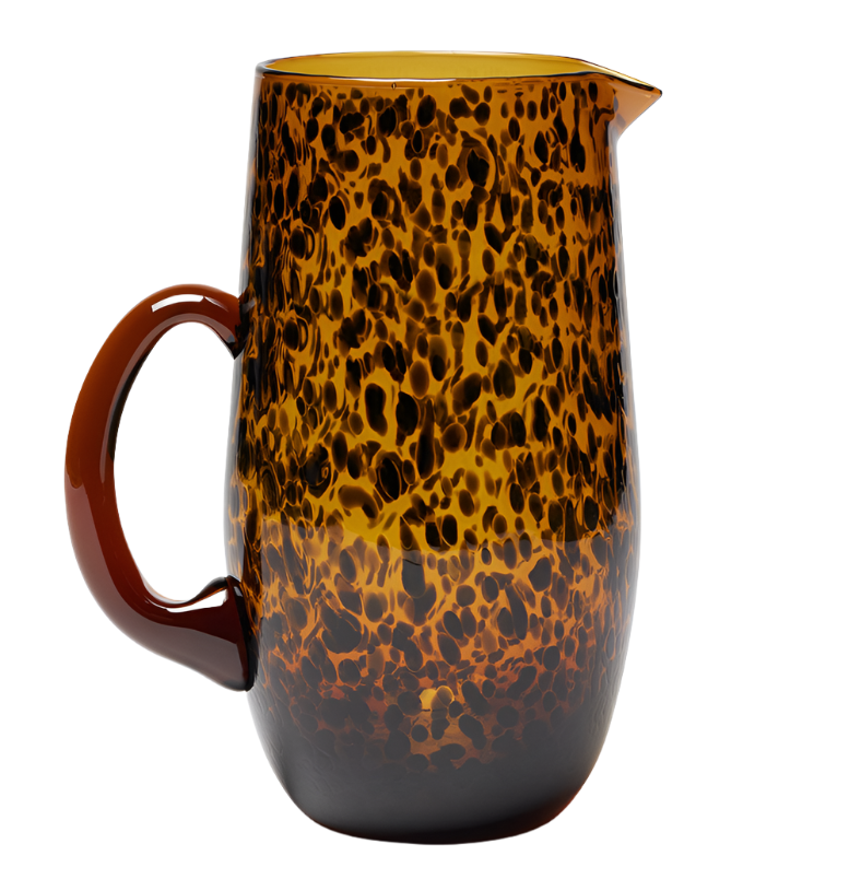 The Blue Pheasant Andrew Tortoise Pitcher, made from hand-blown glass, features a brown and yellow speckled pattern with a solid brown handle—perfect for serving cool cocktails.