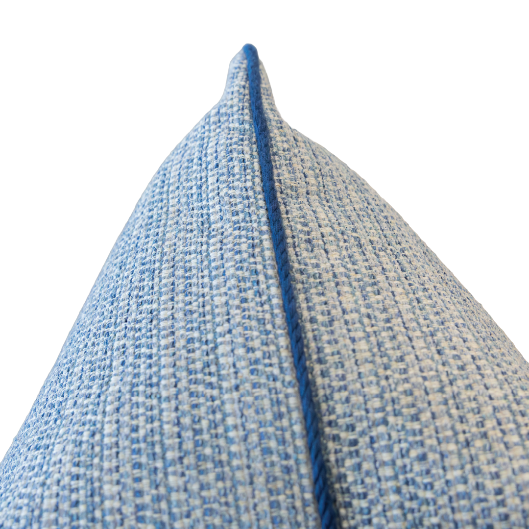 Close-up of the corner of the Roxam Blue Pillow, showcasing its blue and white textured fabric and piped seam, photographed against a white background. This custom pillow features a hidden zipper closure for a seamless look.