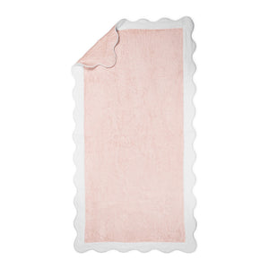 The Neptune Pool Towel in rectangular pink Cairo cotton with a scallop edge is displayed flat, with one corner partially folded over.