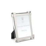 Silver, tarnish-resistant picture frame from the William Yeoward Crystal Classic Clear Frame Collection featuring nickel-plated details and a black backing, designed to stand upright. It gracefully holds an insert labeled "William Yeoward Crystal.