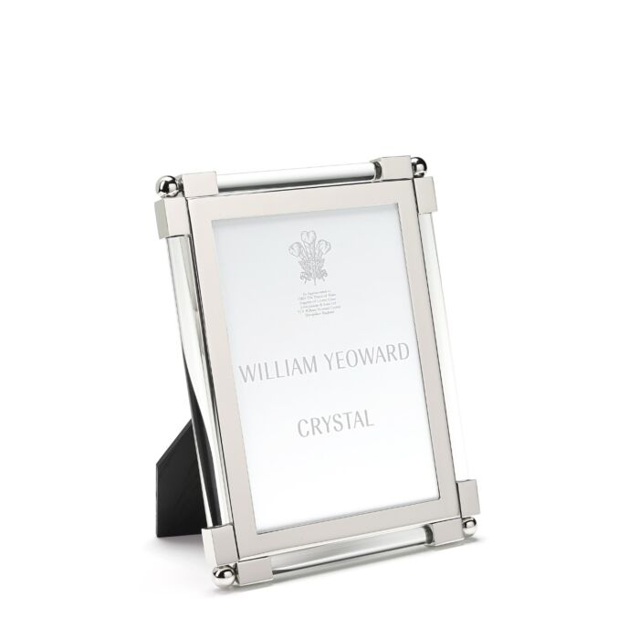 Silver, tarnish-resistant picture frame from the William Yeoward Crystal Classic Clear Frame Collection featuring nickel-plated details and a black backing, designed to stand upright. It gracefully holds an insert labeled "William Yeoward Crystal.