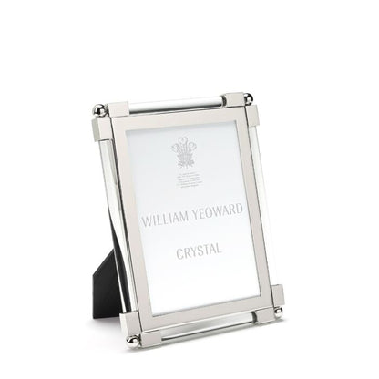 Silver, tarnish-resistant picture frame from the William Yeoward Crystal Classic Clear Frame Collection featuring nickel-plated details and a black backing, designed to stand upright. It gracefully holds an insert labeled "William Yeoward Crystal.