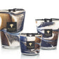 Three Baobab Collection Delta Nil candles of different sizes with swirling brown, white, and blue designs on the glass containers. Each candle has a black label with the Baobab Collection logo, evoking notes of sea salt mixed with hints of papyrus flower.