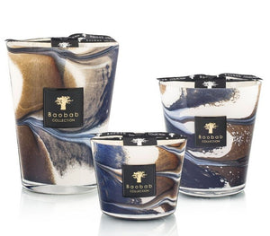 Three Baobab Collection Delta Nil candles of different sizes with swirling brown, white, and blue designs on the glass containers. Each candle has a black label with the Baobab Collection logo, evoking notes of sea salt mixed with hints of papyrus flower.