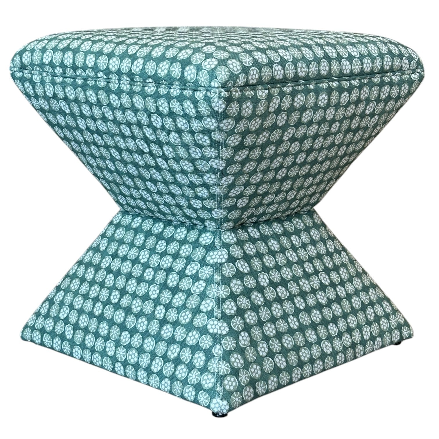 The Hamilton Outdoor Ottoman in Boheme Green features a small hourglass shape with teal fabric and a white circular geometric pattern, making it a chic accent to enhance your patio decor.