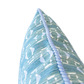 Close-up of the Sicily Outdoor Pillow, featuring a blue fabric adorned with a white geometric pattern and finished with a textured blue piped edge. Expertly crafted from premium materials, this 22x22 pillow is shown against a white background.