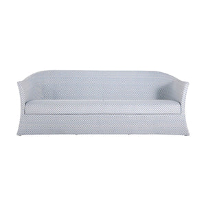 The Bari Sofa in Chambray is a light blue and white striped outdoor sofa with water-resistant cushions, curved arms, a skirted base, and is shown from the front.