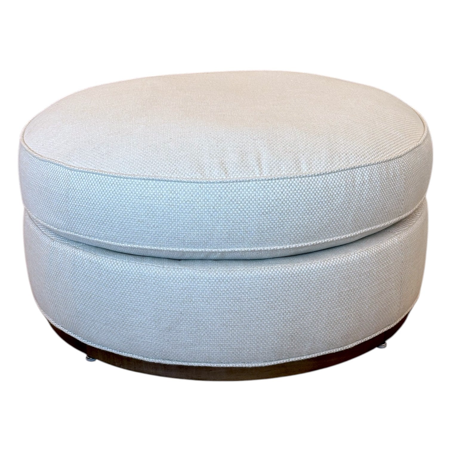 The Bespoke Round Ottoman in Drummond Bone features a cushioned top and dark base, making it an ideal accent piece for any room.