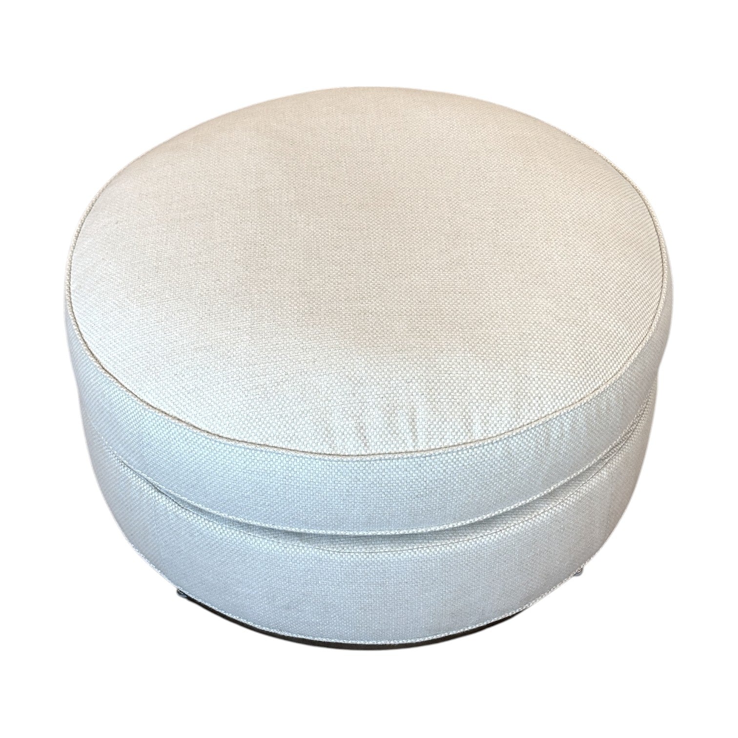 The Bespoke Round Ottoman in Drummond Bone features light beige upholstery, a smooth fabric texture, and a round design—ideal as an accent piece against white backgrounds.