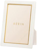 A white picture frame with gold detailing from the AERIN Classic Piero Leather Frame Collection elegantly displaying the word "Aerin" in the center.