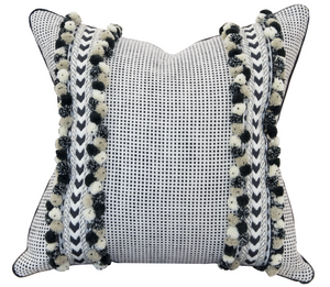 A Kumano Weave Maracana Pom Stripe Pillow with a black and white checkered pattern, adorned with two vertical bands of black and white pom-poms on each side, crafted with special attention to detail.