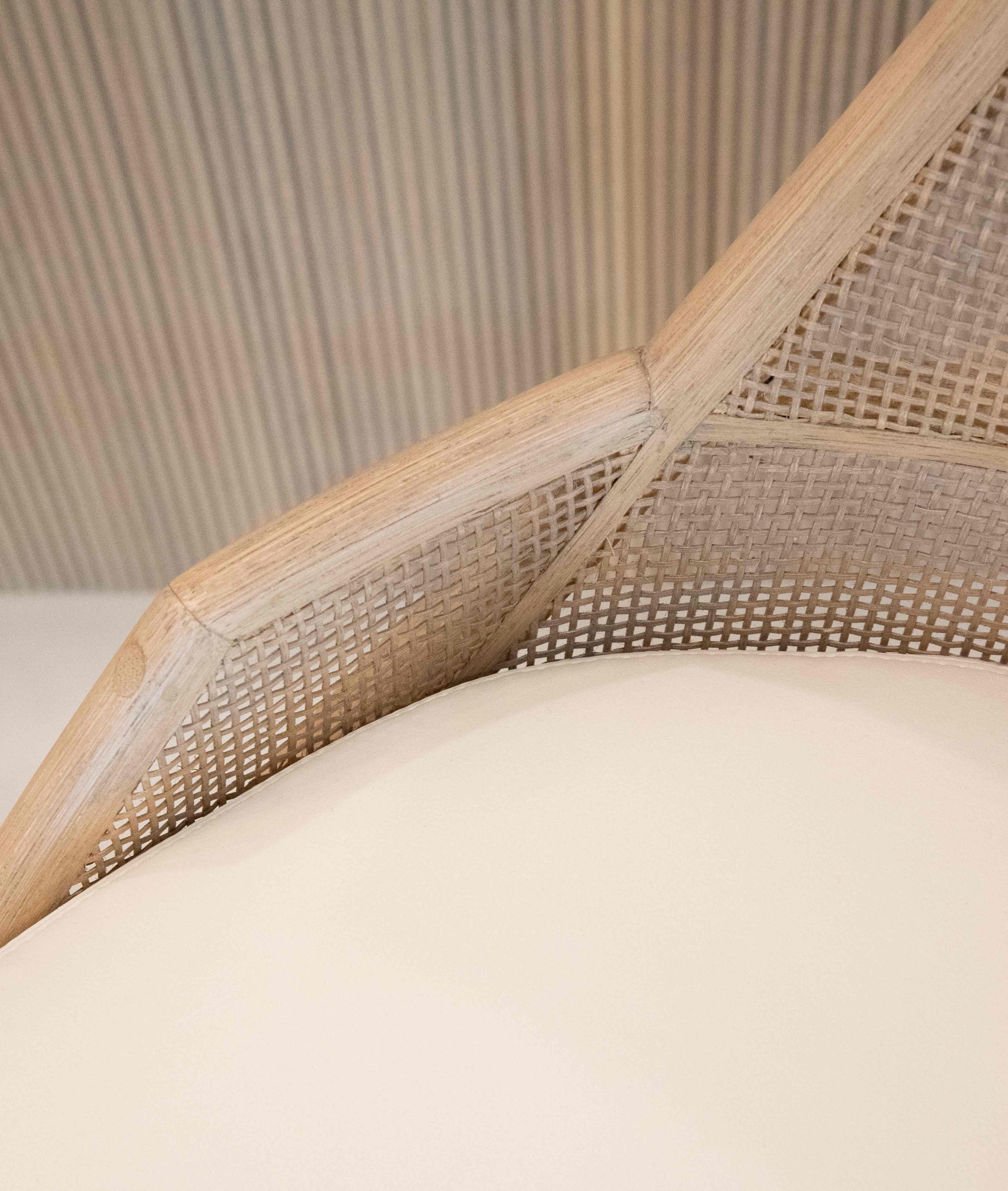 Close-up view of the Hayes Barstool featuring a triangularly shaped wicker backrest with a caned interior and a smooth, round cream-colored cushion.