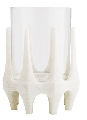 The Harmon Hurricane features a clear cylindrical glass vase nestled in a white textured holder with upward-pointing, evenly spaced prongs, showcasing subtle Brutalist style.