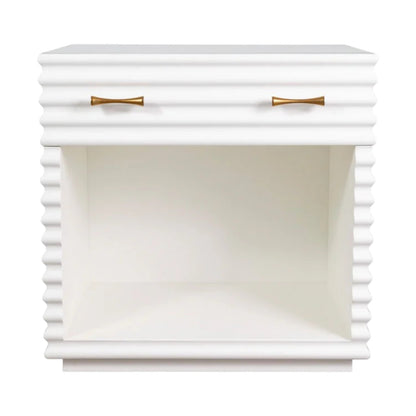 The Brighton Bedside Table has a white satin lacquer finish, ribbed texture, aged brass hardware, a single drawer, and an open storage shelf.