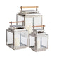 Three Adwin Outdoor Lanterns with silver frames, glass panels, and teak handles, each holding a white pillar candle, are displayed together in small, medium, and large sizes.