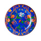 A salad plate from the Mario Luca Giusti Pancale Blue Collection, crafted in blue melamine with an orange and green floral pattern and a prominent white flower in the center, is perfect for adding a touch of elegance to your dinnerware ensemble.