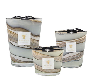 Three Baobab Collection Sand Sonora Candles, infused with notes of saffron and housed in glass containers with marbled patterns and black lids, are displayed in various sizes.