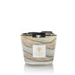 A Baobab Collection Sand Sonora Candle in a glass holder with a layered design and a Baobab Collection label on the front. The candle, infused with notes of saffron, is topped with a black and white ribbon.